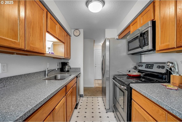 8458 SW Mohawk St, Tualatin, OR 97062 - kitchen featuring appliances with stainless steel finishes, a sink, light flooring, brown cabinets, and a textured ceiling