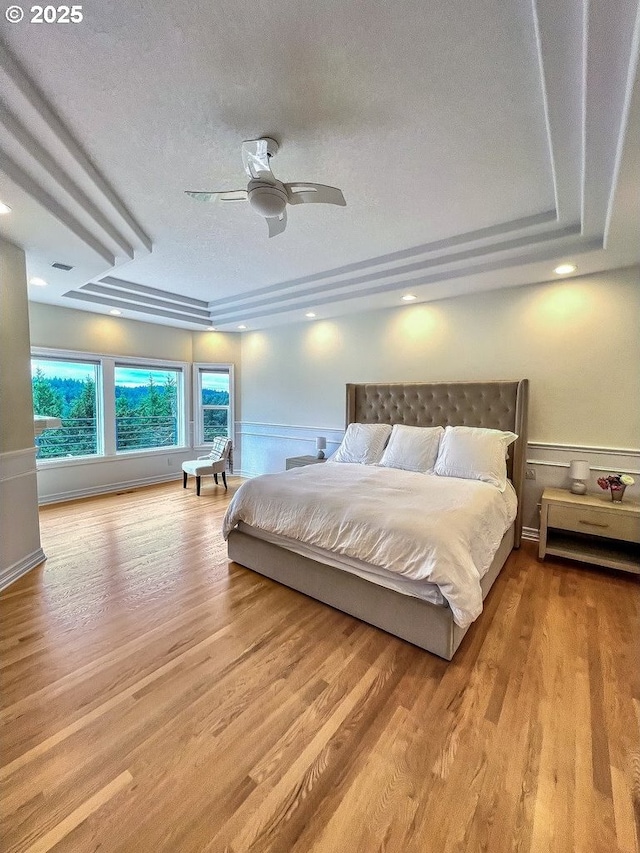 1500 SW Miller Ct, Gresham, OR 97080 - bedroom with a raised ceiling, wood finished floors, a textured ceiling, wainscoting, and a ceiling fan