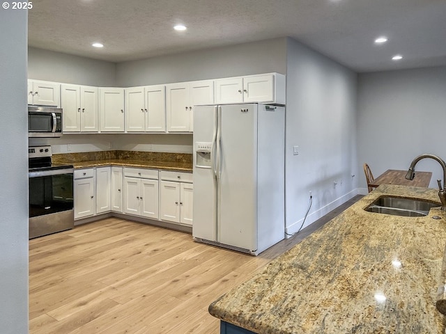 1500 SW Miller Ct, Gresham, OR 97080 - kitchen featuring appliances with stainless steel finishes, a sink, stone counters, light wood finished floors, and white cabinetry