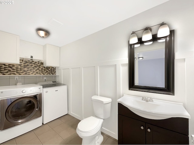 bathroom featuring a wainscoted wall, tile patterned flooring, toilet, and washer and dryer