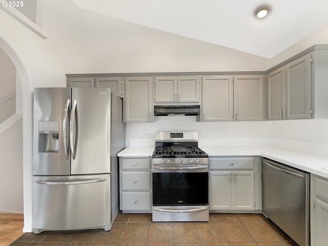 kitchen with appliances with stainless steel finishes, vaulted ceiling, light countertops, gray cabinetry, and under cabinet range hood