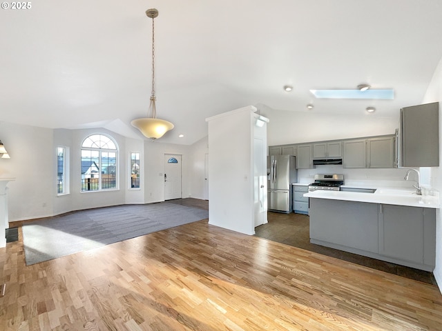 kitchen with gray cabinets, stainless steel appliances, light countertops, under cabinet range hood, and a sink