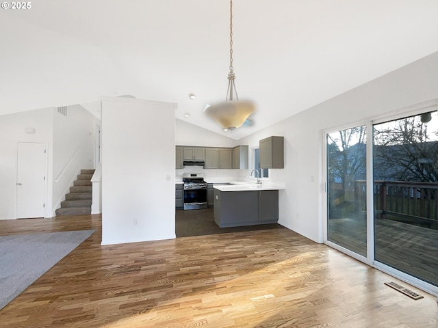 kitchen with gray cabinets, light countertops, gas stove, wood finished floors, and under cabinet range hood