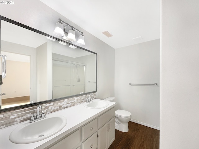 bathroom featuring wood finished floors, backsplash, a sink, and visible vents