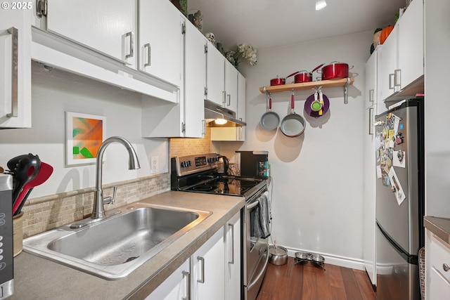 7522 SW Barnes Rd Unit E, Portland, OR 97225 - kitchen featuring appliances with stainless steel finishes, under cabinet range hood, dark wood-style flooring, backsplash, and white cabinetry