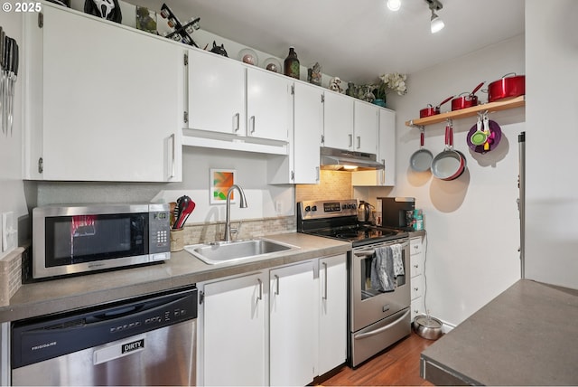 7522 SW Barnes Rd Unit E, Portland, OR 97225 - kitchen featuring stainless steel appliances, under cabinet range hood, white cabinetry, wood finished floors, and tasteful backsplash