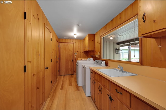 996 Lariat Dr, Eugene, OR 97401 - laundry room with washer and clothes dryer, cabinet space, light wood finished floors, and wood walls