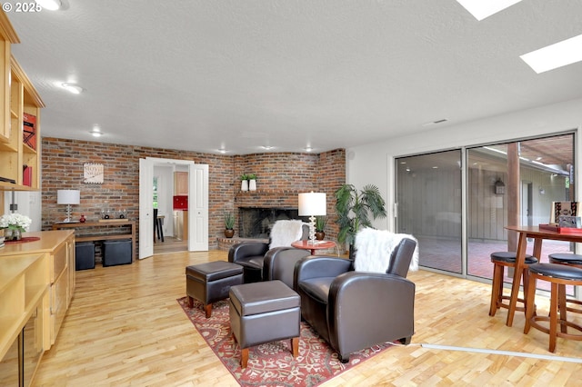 996 Lariat Dr, Eugene, OR 97401 - living area featuring light wood-type flooring, a skylight, brick wall, a fireplace, and a textured ceiling