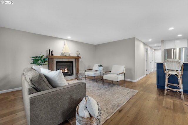 living room with light wood-type flooring and a tiled fireplace