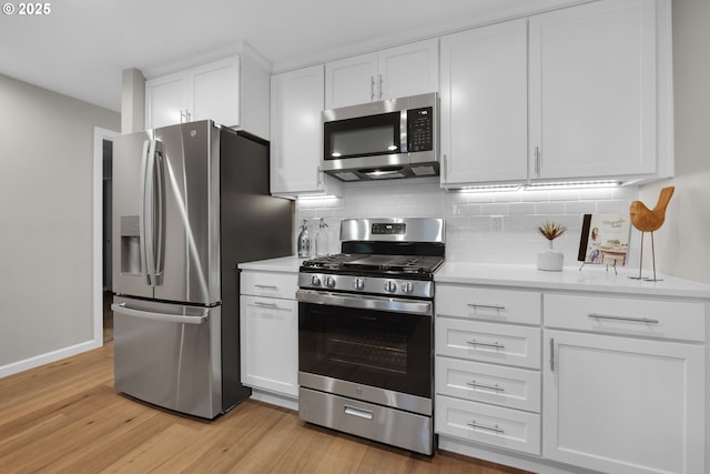 kitchen featuring white cabinets, backsplash, appliances with stainless steel finishes, and light hardwood / wood-style floors