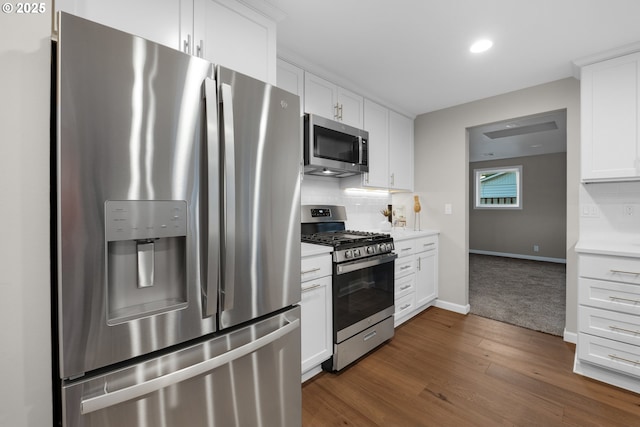 kitchen featuring stainless steel appliances, white cabinetry, and tasteful backsplash