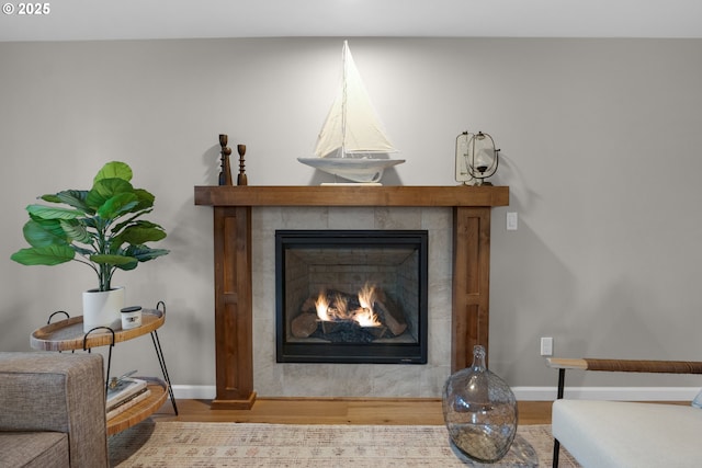 interior details featuring wood-type flooring and a tiled fireplace