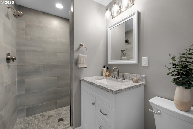 bathroom featuring toilet, vanity, and a tile shower