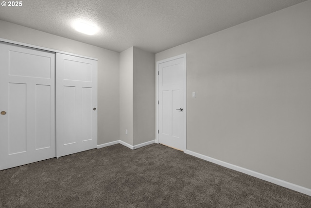 unfurnished bedroom featuring a closet, dark carpet, and a textured ceiling