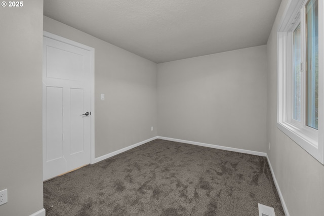 unfurnished room featuring dark colored carpet