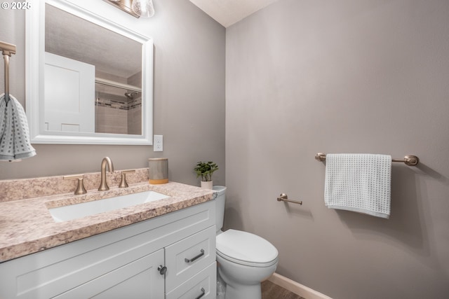 bathroom featuring toilet, vanity, and an enclosed shower