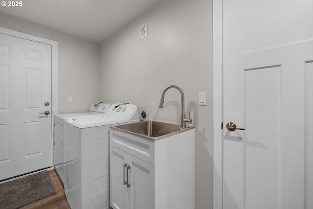 clothes washing area featuring cabinets, dark wood-type flooring, washing machine and clothes dryer, and sink