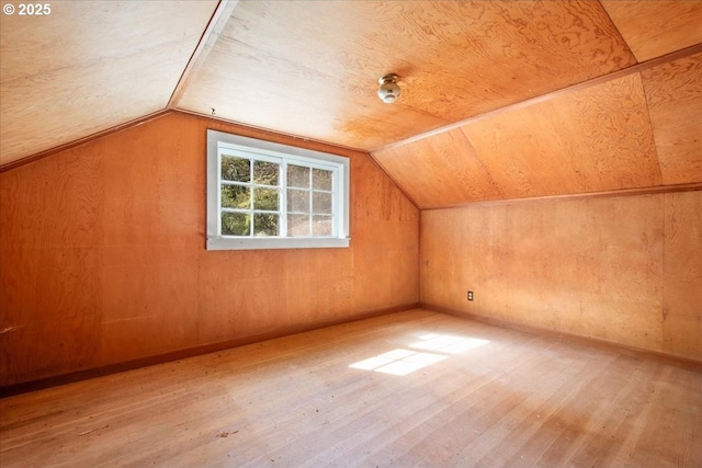 bonus room featuring hardwood / wood-style flooring, wood walls, and vaulted ceiling