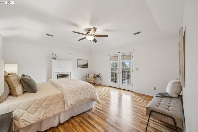 213 Hidalgo St, Lake Oswego, OR 97035 - bedroom featuring access to exterior, light wood-style floors, a glass covered fireplace, a ceiling fan, and french doors