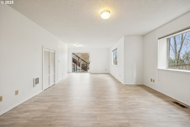 213 Hidalgo St, Lake Oswego, OR 97035 - unfurnished living room featuring plenty of natural light, light wood-style flooring, a textured ceiling, and baseboards