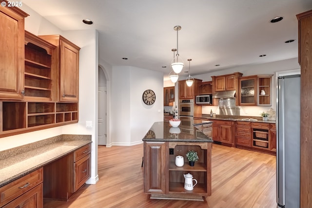 kitchen featuring a kitchen island, pendant lighting, dark stone counters, stainless steel appliances, and light hardwood / wood-style flooring