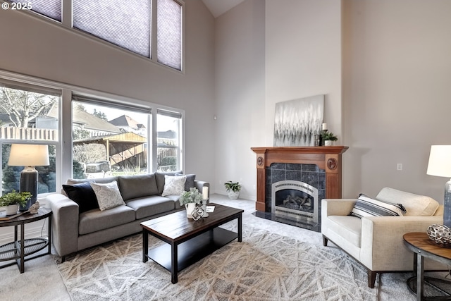 carpeted living room with a towering ceiling and a tiled fireplace