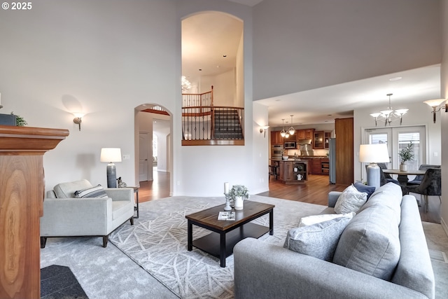 living room with a notable chandelier, a towering ceiling, and light hardwood / wood-style flooring