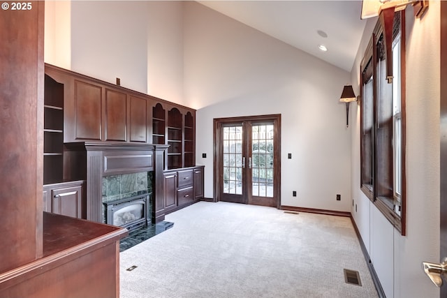 home office with light colored carpet, a fireplace, high vaulted ceiling, and french doors