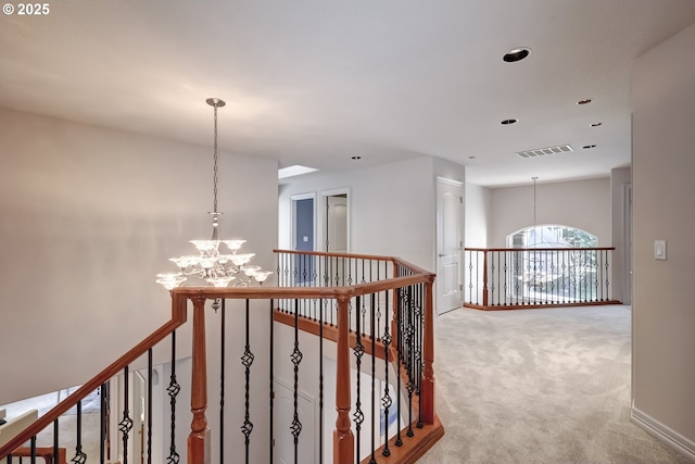 hall featuring carpet and a chandelier