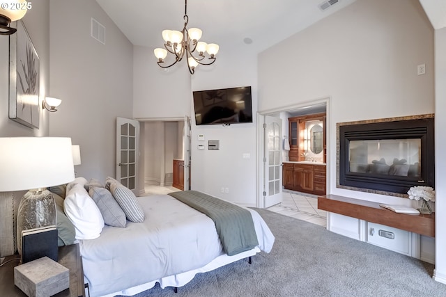 carpeted bedroom with a notable chandelier, high vaulted ceiling, ensuite bathroom, and a multi sided fireplace