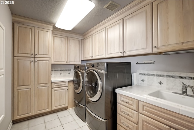 clothes washing area with sink, cabinets, light tile patterned floors, independent washer and dryer, and a textured ceiling