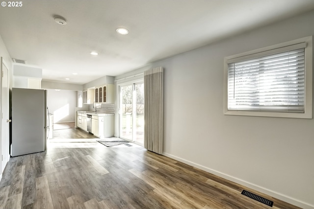 unfurnished living room with visible vents, baseboards, and dark wood finished floors