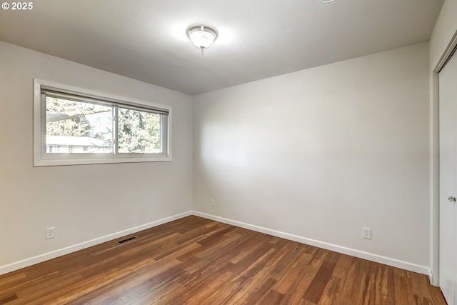 empty room featuring visible vents, baseboards, and wood finished floors