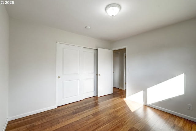 unfurnished bedroom featuring a closet, baseboards, and wood finished floors