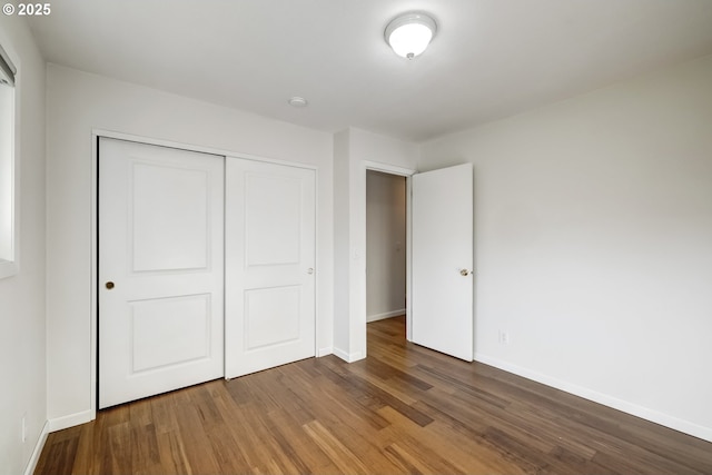 unfurnished bedroom with wood finished floors, a closet, and baseboards