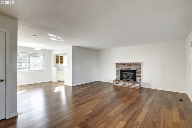 unfurnished living room featuring dark wood-style floors, visible vents, a fireplace, and baseboards