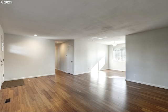 spare room featuring visible vents, baseboards, and dark wood-style flooring