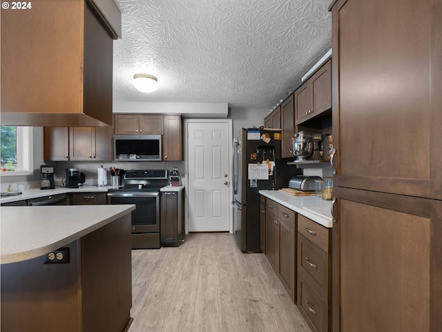 1890 NW 6th Dr, Gresham, OR 97030 - kitchen featuring stainless steel appliances, light countertops, light wood finished floors, and a textured ceiling
