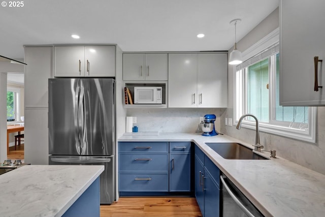 kitchen featuring a sink, blue cabinetry, light stone countertops, and stainless steel appliances