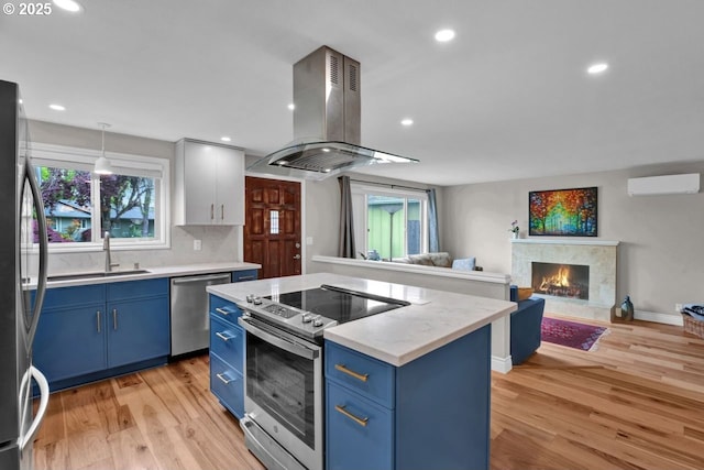 kitchen featuring a wall mounted AC, stainless steel appliances, blue cabinets, and island range hood