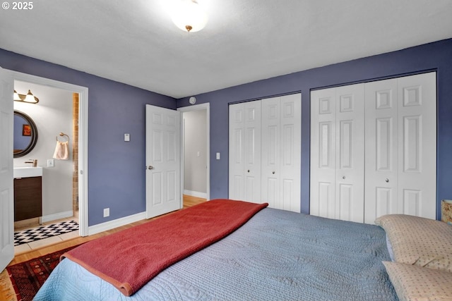 bedroom with baseboards, multiple closets, and ensuite bath