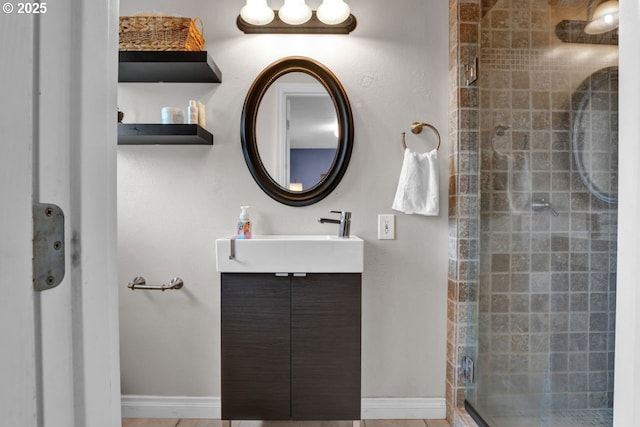 bathroom featuring baseboards, a shower stall, and vanity