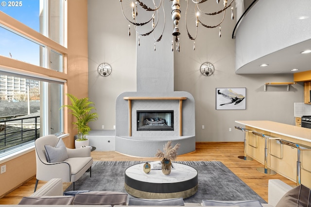 living room with a fireplace, light wood-type flooring, and an inviting chandelier