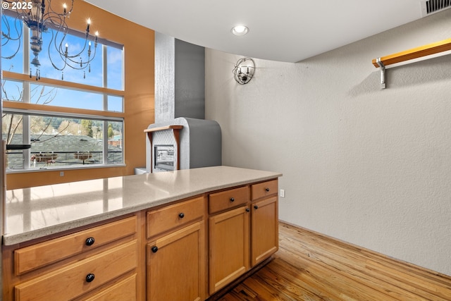 kitchen featuring a chandelier, light hardwood / wood-style flooring, and light stone countertops