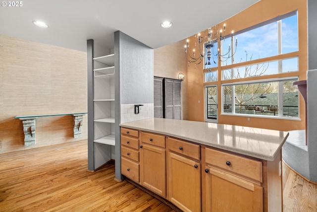 kitchen with plenty of natural light, light wood-type flooring, kitchen peninsula, and a chandelier