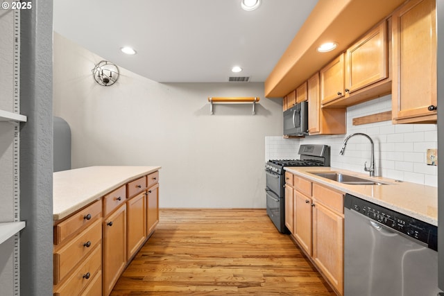 kitchen with backsplash, black gas stove, sink, stainless steel dishwasher, and light wood-type flooring