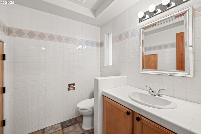 bathroom featuring vanity, toilet, and tile walls