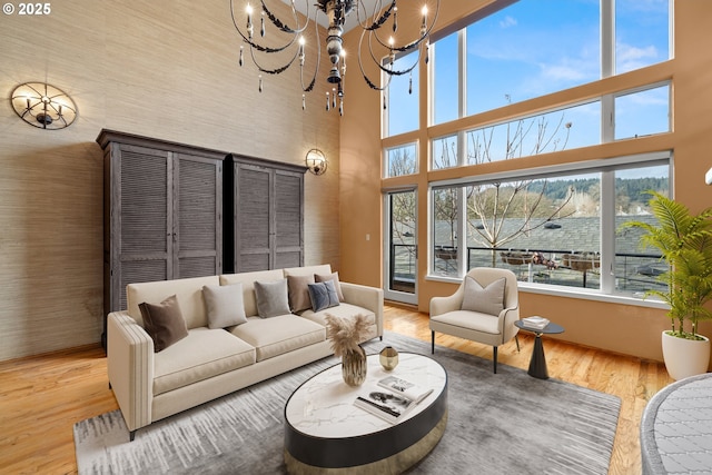 living room featuring a towering ceiling, a chandelier, and hardwood / wood-style flooring