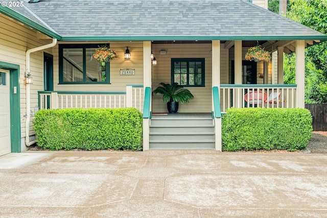 view of exterior entry with a porch, roof with shingles, and an attached garage