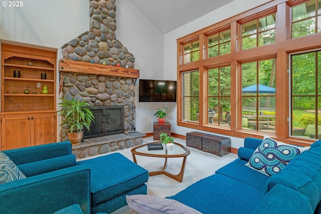 carpeted living area with a stone fireplace, healthy amount of natural light, high vaulted ceiling, and a textured ceiling